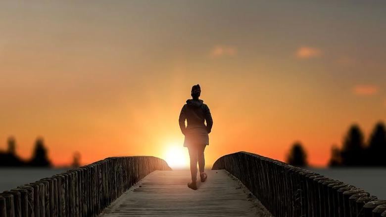 日落时分，一位妇女站在湖上的桥上