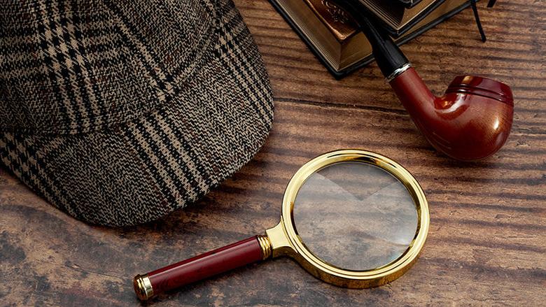 Sherlock Holmes magnifying glass, cap, pipe, and books